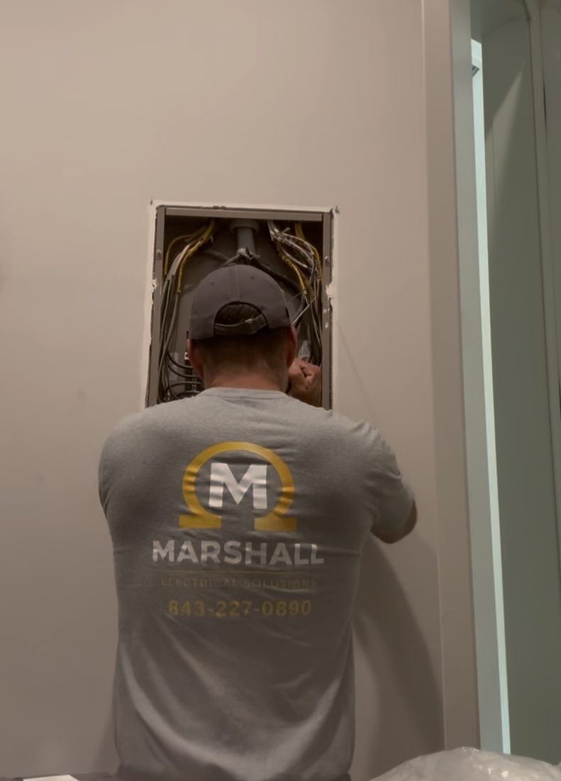 Rob Marshall in a branded Marshall Electrical Solutions shirt working at an open electrical panel